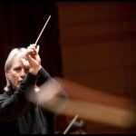 Music Director Carl St.Clair holding a baton up.